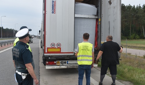 Inspektor Wojewódzkiego Inspektoratu Ochrony Środowiska w Warszawie oraz funkcjonariusz Policji kontrolują samochód ciężarowy.